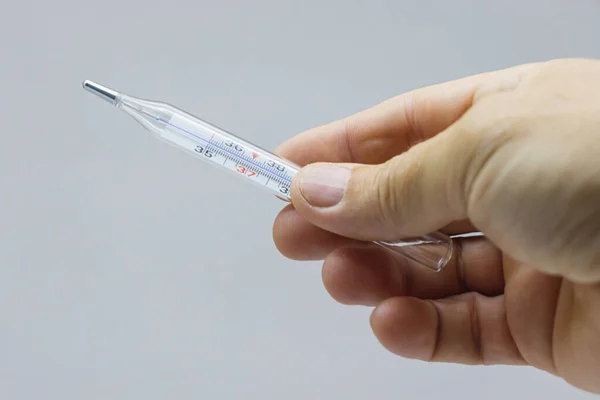 Mercury thermometer to measure body temperature in the hand.