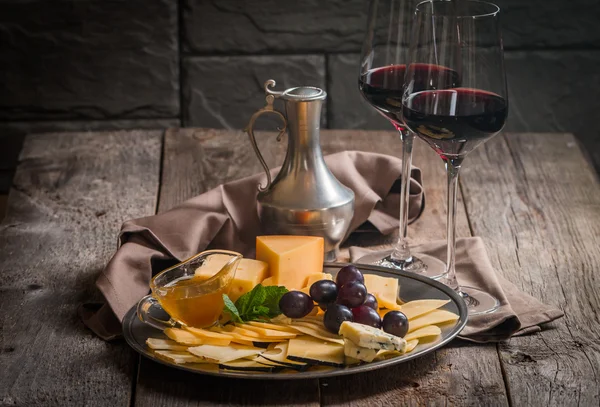 Bodegón refinado de vino tinto, uvas y queso — Foto de Stock