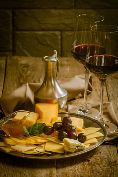Bodegón refinado de vino tinto, uvas y queso — Foto de Stock