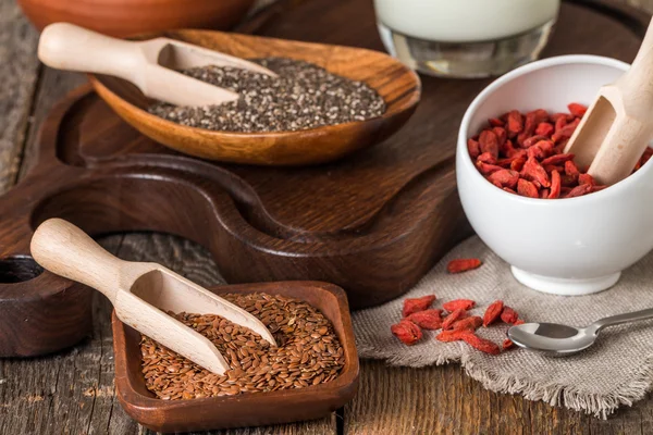 Semillas y goji en cucharas de madera — Foto de Stock