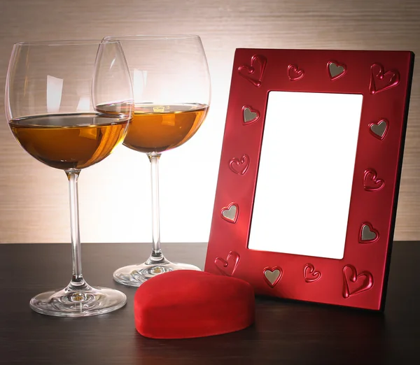 Due bicchieri di vino, cuore rosso e cornice fotografica . — Foto Stock