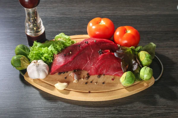Rohes Rindfleisch mit Gemüse auf Holztisch — Stockfoto