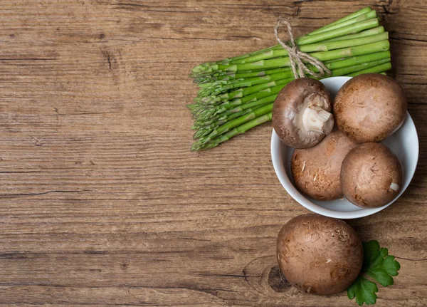 Bunch of asparagus and mushrooms on wooden table — Stock Photo, Image