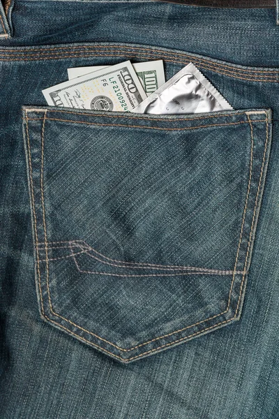 Nas dolary i prezerwatywy w kieszeni jeansów — Zdjęcie stockowe