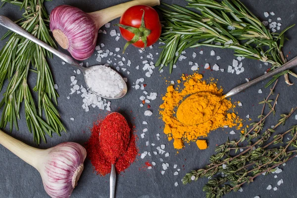 Spoons with spices and herbs on  black — Stock Photo, Image