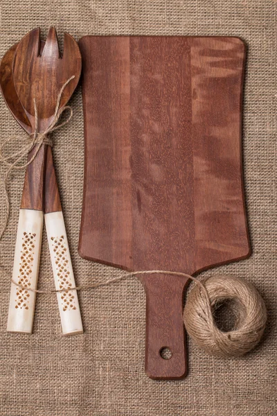 Wooden cutting board, spoon and fork — Stock Photo, Image