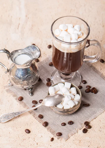 Coupe en verre de café avec guimauve, pot de lait et grains de café — Photo