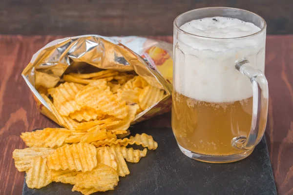 Beer with foam in glass mug and potato chips — Stock Photo, Image