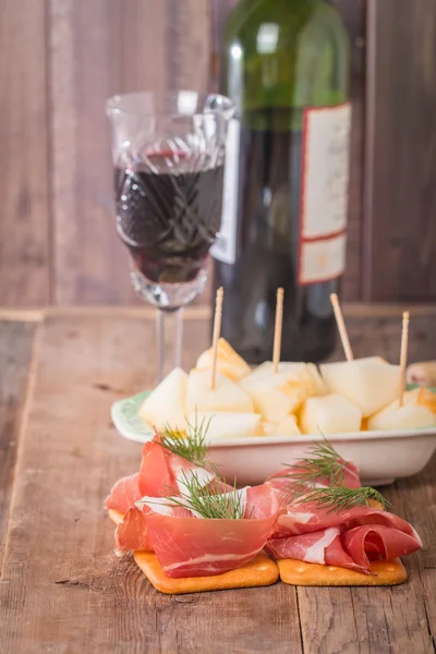 Slices of cured ham with melon and red wine — Stock Photo, Image