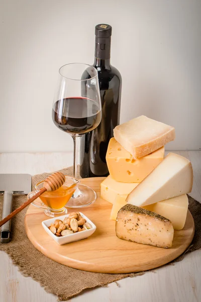 Placa de queso surtido con vino tinto, frutos secos y miel — Foto de Stock