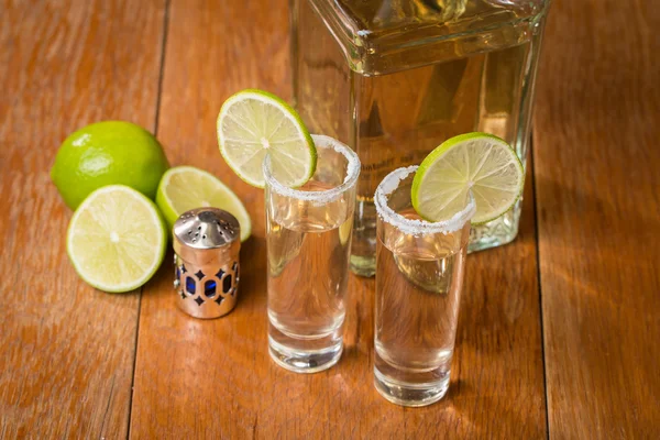 Tequila de ouro em copos de tiro com limão e sal — Fotografia de Stock