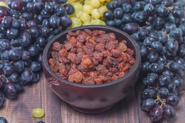Raisins in bowl and grapes — Stock Photo, Image
