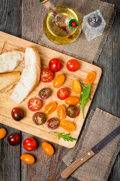 Fresh colorful tomatoes, olive oil and bread — Stock Photo, Image
