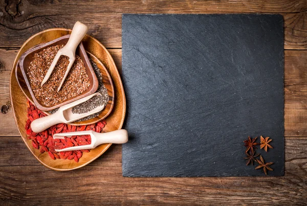 Semillas y goji en cucharas de madera — Foto de Stock