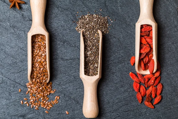 Semillas y goji en cucharas de madera — Foto de Stock