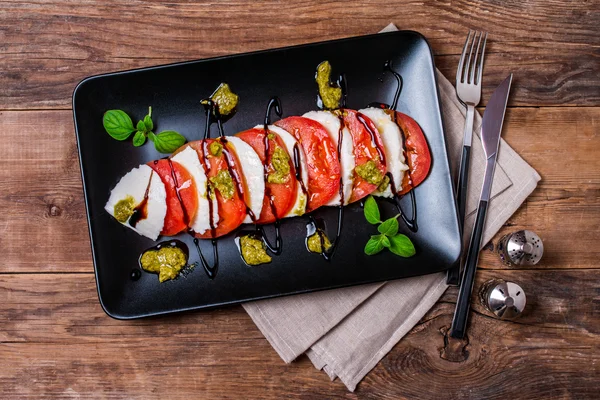 Ensalada Caprese en plato negro — Foto de Stock