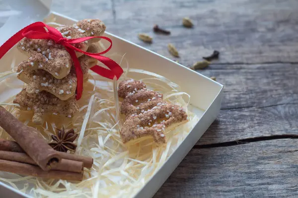 Biscotti di pan di zenzero di Natale in una confezione regalo con nastro di raso rosso, cannella, anice, cardamomo e spezie di chiodi di garofano su sfondo lavagna con spazio per il testo — Foto Stock