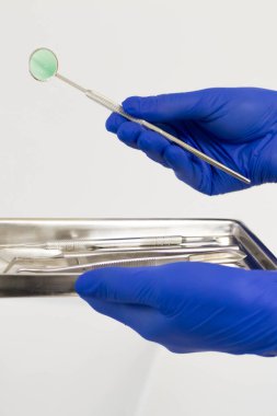 Ofisteki dişçilerin kullandığı dişçi aletleri ve diğer erişim araçları. Diş kliniğinde diş aletleri tutmanın ayrıntıları. Diş aletleri. Mavi bir tıbbi eldiven verin. Dişçi Konsepti