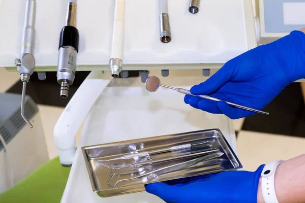 Ofisteki dişçilerin kullandığı dişçi aletleri ve diğer erişim araçları. Diş kliniğinde diş aletleri tutmanın ayrıntıları. Diş aletleri. Mavi bir tıbbi eldiven verin. Dişçi Konsepti
