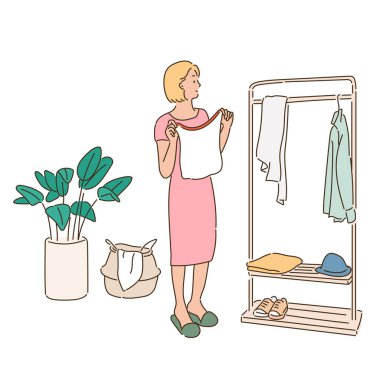 A woman is choosing clothes from hangers in a wardrobe.