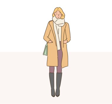  A fashionable woman is standing in a long coat. hand drawn style vector design illustrations.