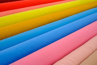 çok renkli desenler, kumaş rulolarının yan yana oluşturduğu, çerçevede köşegen biçiminde parlak renkler.