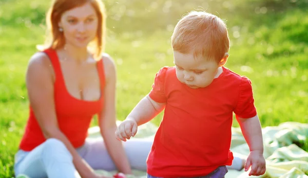 La maternidad, un paseo por el parque con el bebé, el verano caluroso, la hora de verano para picnic con su familia, madre e hijo, hijo, hija, bebé, niño serio aprende — Foto de Stock