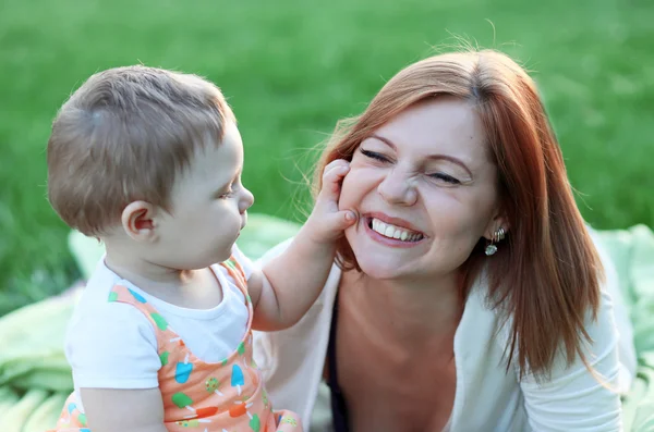 Anne ve kızı parkta bir çayırda dinleniyor. Bebek anne ile oynuyor. bir yürüyüş çocuk annesiyle. Çocuk games.young anne. Gerçek duygular. Anne ve çocuk iletişim. Samimi bir gülümseme. Mutlu annelik. Telifsiz Stok Fotoğraflar