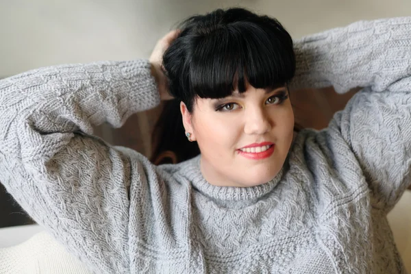 Brunette collects hair in a ponytail,thick hair,making hairstyle,leaned back,resting on the sofa,relaxing after a long for,tired woman,prevent hair,hands apart,removes hair,plus size model,She threw her head,arched her back,plait braids,haired — Stock Photo, Image