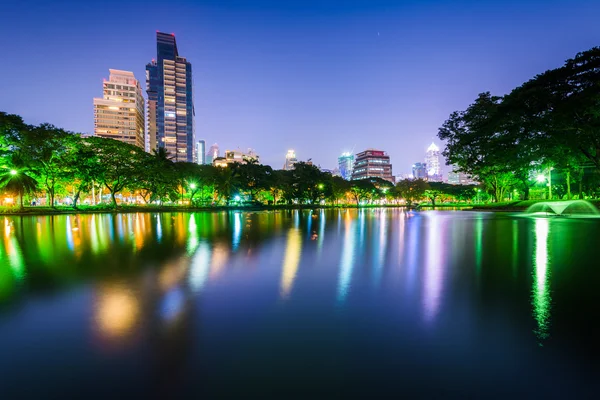 Lago y rascacielos por la noche, en Lumphini Park, en Bangkok, Tha — Foto de Stock