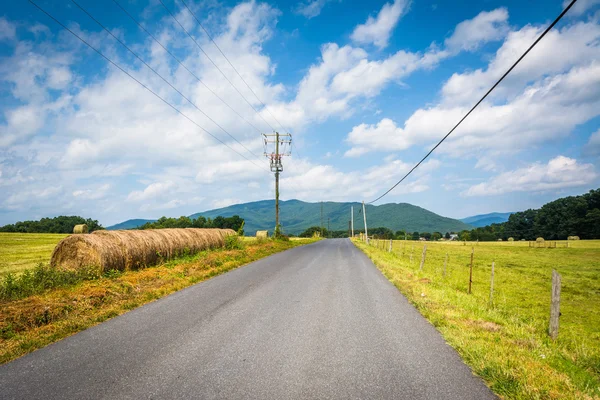 Landweg met bergen in de verte en velden van de boerderij in de landelijke — Stockfoto