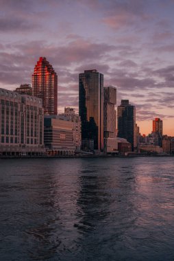 Nehirli bir şehir silüeti, New York Roosevelt Adası 'ndan günbatımında Manhattan' ın yukarı manzarası.