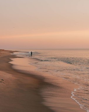Güneş doğarken kıyıda, Nags Head, Kuzey Carolina 'da balıkçı.