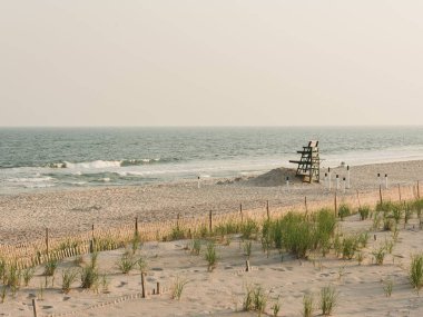 Cankurtaran, New York 'taki Fire Island' daki kum tepecikleri ve okyanus manzarasıyla ayakta duruyor.