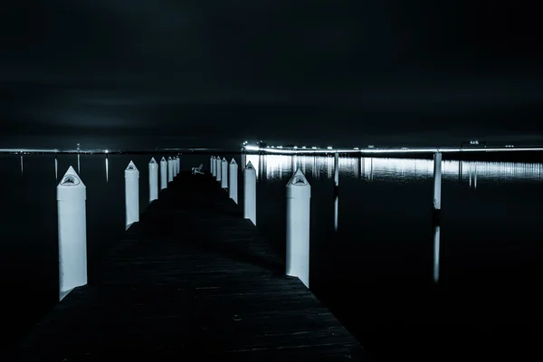 A pier and the Chesapeake Bay Bridge at night, in Kent Island, M — Stock Photo, Image