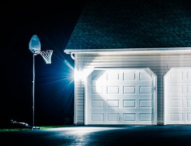 Garage and basketball hoop at night.  clipart