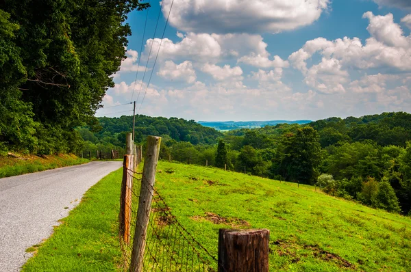 Fence and rural backroad atop a hill in Baltimore County, Maryla — Stock Photo, Image