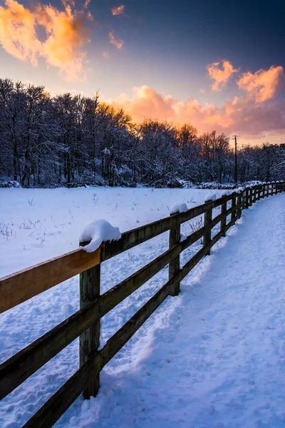 Recinzione su un campo innevato al tramonto, nella contea rurale di York, P — Foto Stock