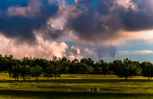 Sonnenuntergang Wolken über Bäumen und Wanderer auf einem Pfad in großen Wiesen, s — Stockfoto