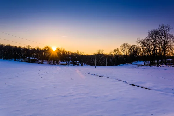 農村のヨーク郡、ペンシルバニアの雪に覆われたファーム フィールドに沈む夕日 — ストック写真