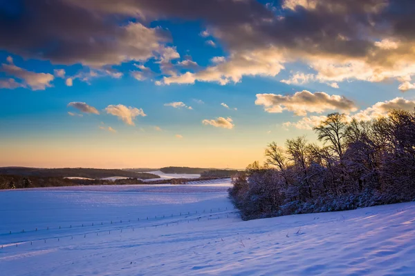 Vista di colline innevate e campi agricoli al tramonto in — Foto Stock