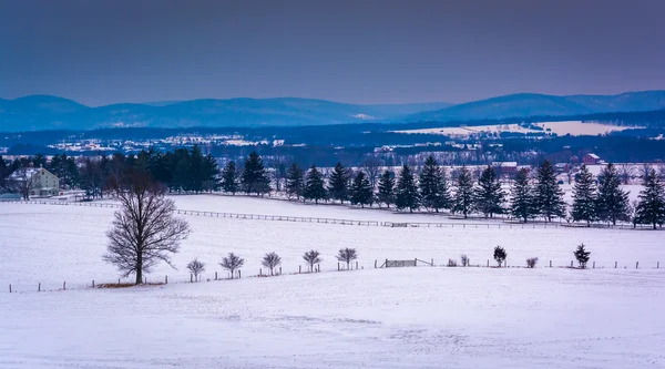 Karla kaplı tarım alanları ve uzun mesafeli dağlardan görünümü — Stok fotoğraf
