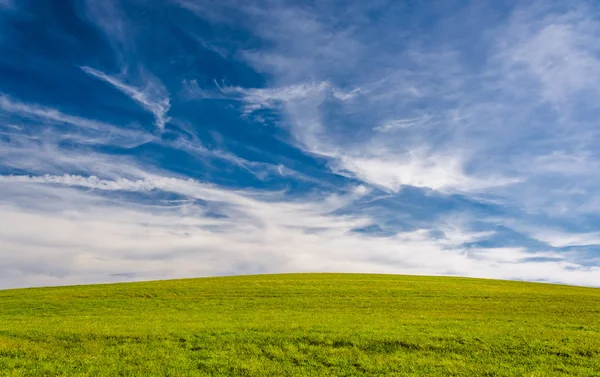 Onregelmatige wolken boven een met gras begroeide heuvel in york county, pennsylvania. — Stockfoto