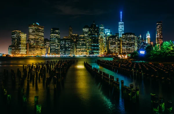 Pier pilings and the Manhattan skyline at night, seen from Brook — Stock Photo, Image
