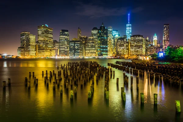 Pier pilings és a manhattan látképének éjjel, látható a patak — Stock Fotó