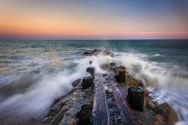 Waves and a jetty at sunset in the Atlantic Ocean at Edisto Beac — Stock Photo, Image