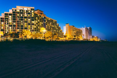 Tire tracks on the beach and hotels at night, in Daytona Beach,  clipart