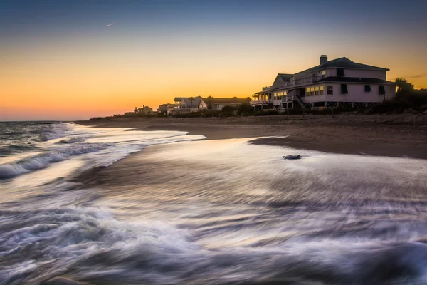 Bølger i Atlanterhavet og strandhus ved solnedgang. – stockfoto