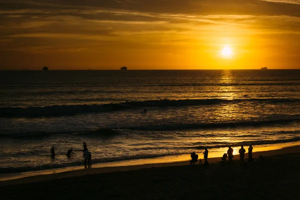 Les gens sur la plage et le coucher du soleil sur l'océan Pacifique à la chasse — Photo