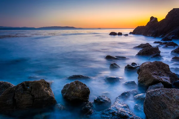 Lange Belichtung von Wellen, die auf Felsen an der Pelikanbucht bei Sonnen krachen — Stockfoto